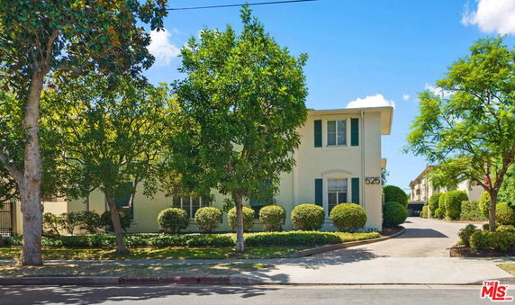 Front view of a two-story house with trees and driveway.