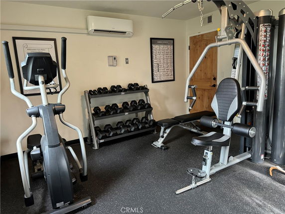 Indoor gym area with exercise equipment and weights.
