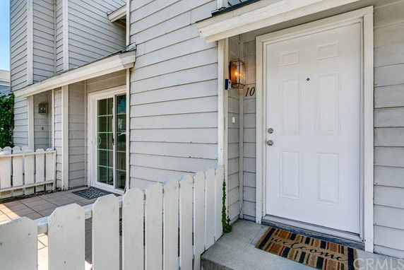 Front view of a house with light gray siding and a white front door.