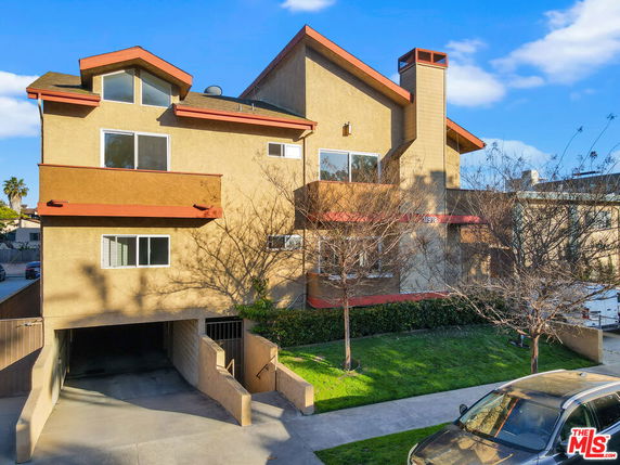 Front view of a multi-story house with a sloped roof and a chimney.