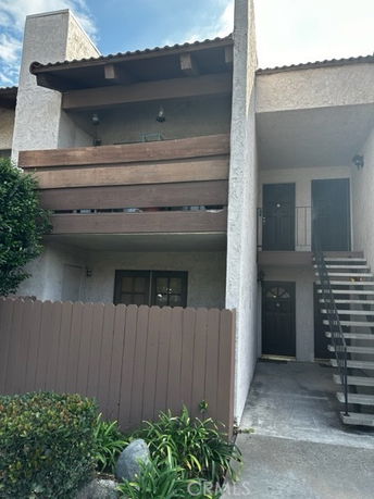 Front view of a two-story building with a balcony and external staircase.