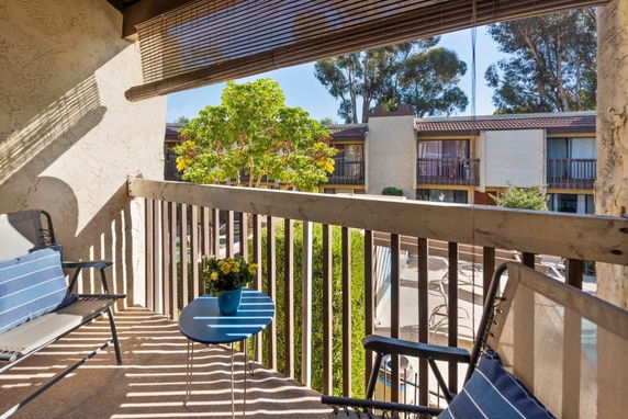 View from a balcony overlooking a residential complex with trees and multiple buildings.