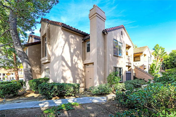 Front view of a two-story house with a beige exterior and tiled roof.