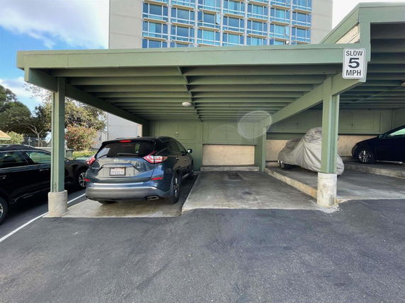 Covered parking area with vehicles beneath a structure.