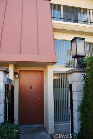 Entrance view of a two-story building with a red door and large windows.
