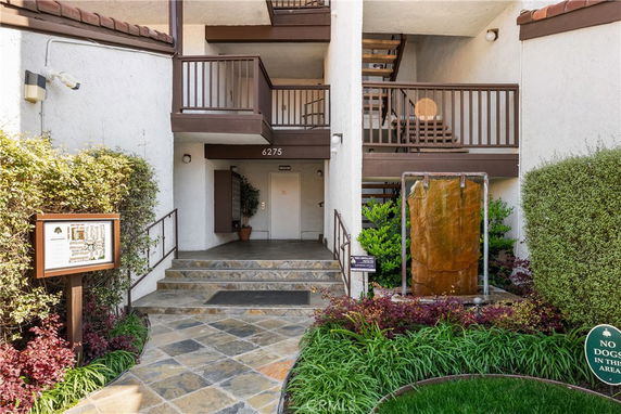 Entryway of a multi-story residential building with stairs and balconies.
