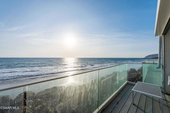 Panoramic view of ocean from a balcony with glass railing.