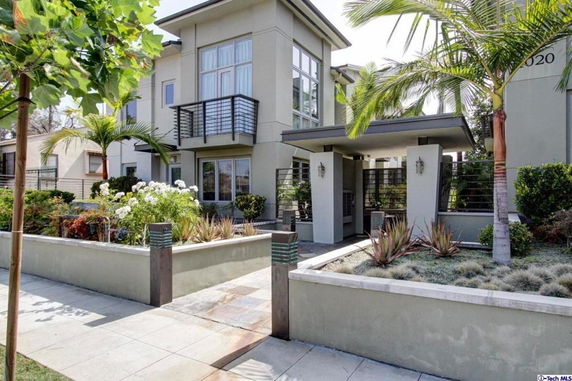 Front view of a modern multi-story house with balconies and tall windows.