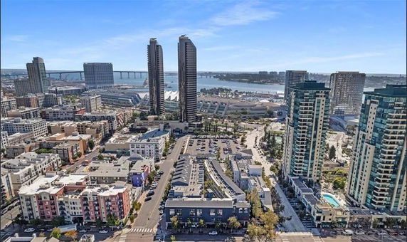 Wide-angle view of a cityscape with tall buildings and a bridge in the background.
