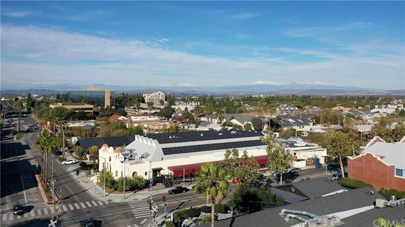 Aerial view of a commercial area with buildings, roads, and distant mountains.