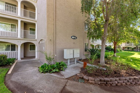 Front view of a multi-story building with balconies and a small garden area.