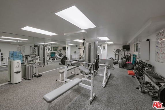 Indoor gym with various exercise equipment and a mirrored wall.