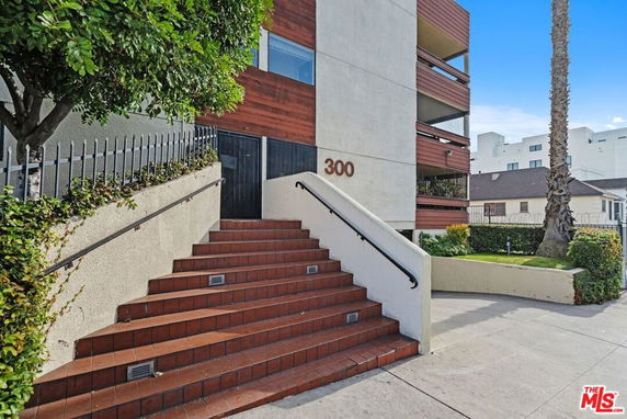 Front view of a multi-story building with brown paneling and steps leading to the entrance.