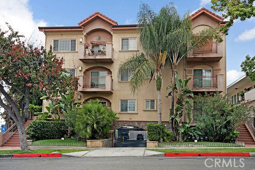 Front view of a multi-story residential building with balconies and a central entrance.