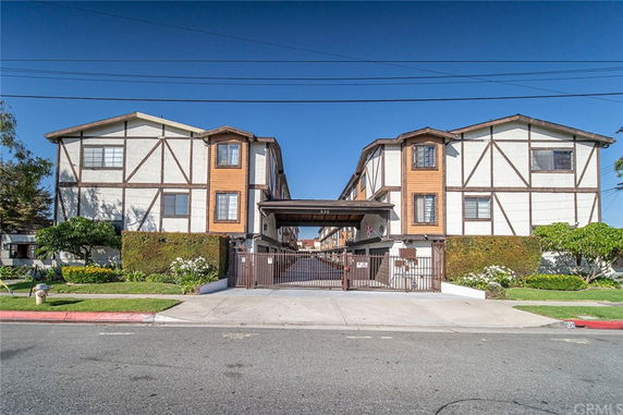 Front view of two three-story residential buildings with decorative timber framework and gated entrance.