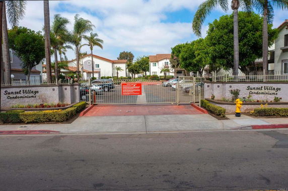 Front view of a condominium complex with gated entrance and surrounding trees.