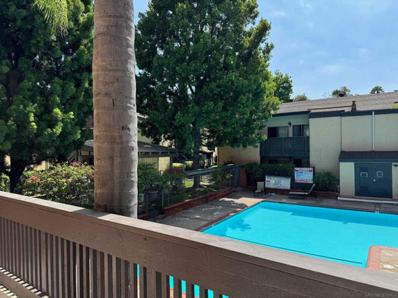 Outdoor swimming pool next to a two-story building with balconies.