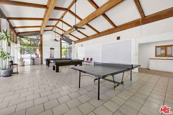Room with billiards and ping pong tables, high ceiling with wooden beams.