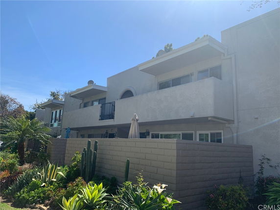 Front view of a two-story building with balconies and solid wall.