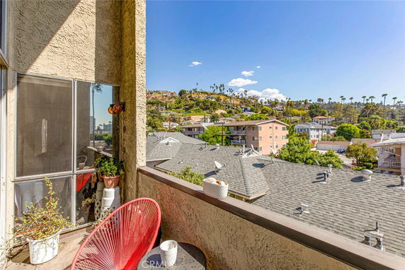 Panoramic view from a balcony overlooking rooftops and surrounding hills.