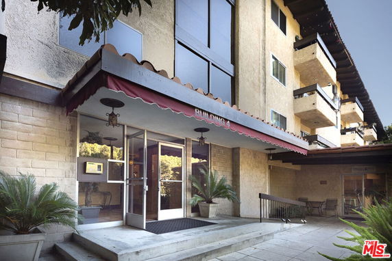 Front view of a multi-story residential building with balconies and an entrance canopy.