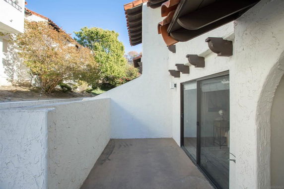 View from a building showing a patio with sliding glass doors and surrounding greenery.