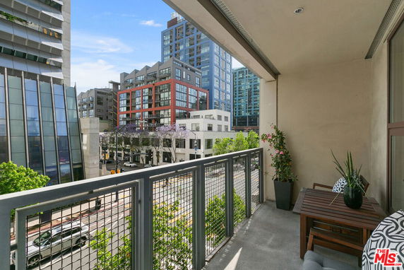 View from a balcony overlooking city buildings and a busy street.