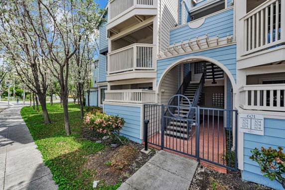 Front view of a multi-story residential building with balconies and an arched entrance.