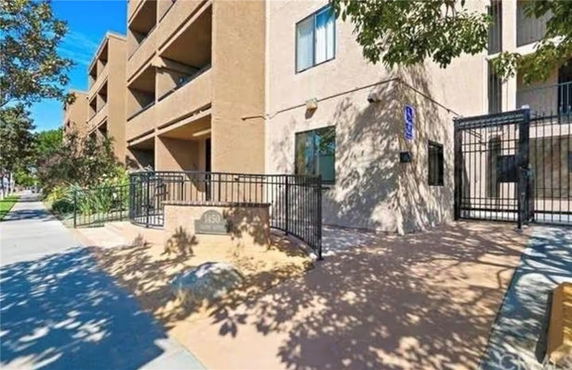 Front view of a multi-story apartment building with balconies and gated entrance.