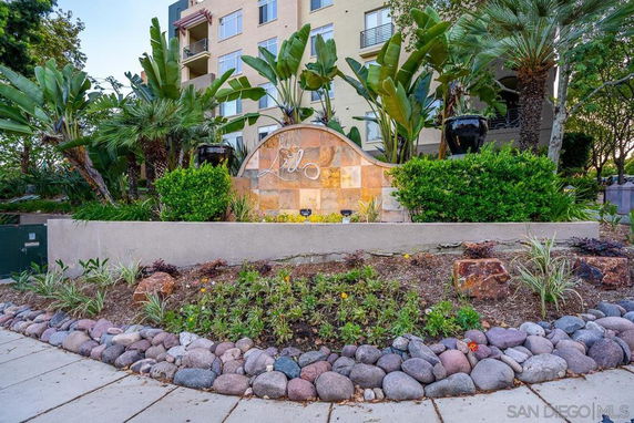 Front view of a multi-story residential building with landscaped area and signage.