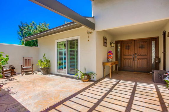 Front view of a house with a shaded entrance and large double doors.