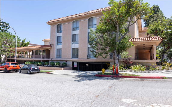 Front view of a multi-story building with a tiled roof and covered parking.