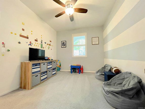 Indoor play area with a TV, storage unit, small table, and bean bag chairs.