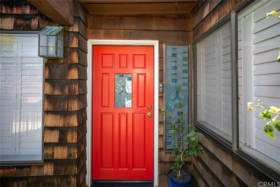 Front entrance of a house with a red door and wooden siding.