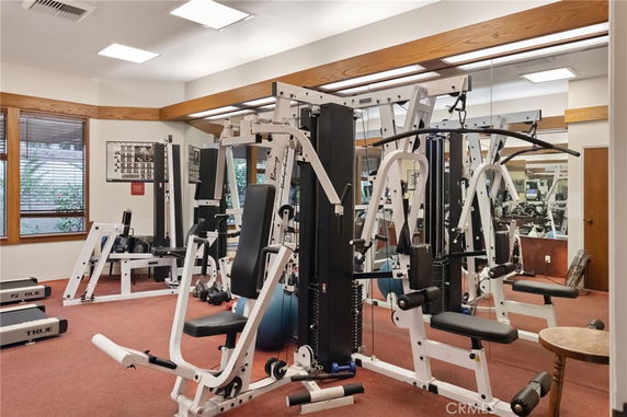 Indoor gym area with exercise machines and mirrors.