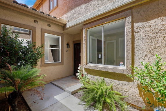 Front view of a two-story house with a small entrance area and plants.