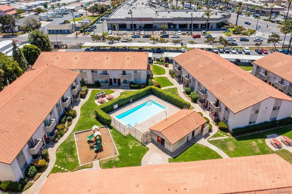 Panoramic aerial view of apartment complex with central swimming pool and surrounding area.
