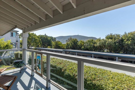 View from a balcony overlooking a parking area and distant hills.
