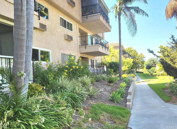 Side view of a multi-story residential building with balconies and surrounding greenery.