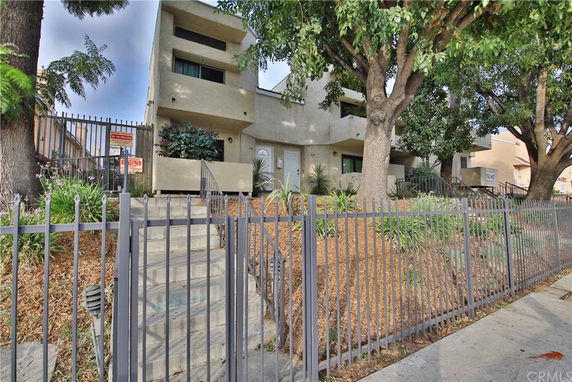 Front view of a multi-story apartment building with a gated entrance.