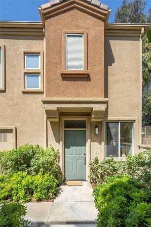 Front view of a two-story house with a green door and stucco exterior.