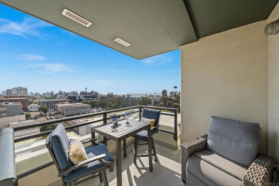 Balcony with seating and a view of the surrounding urban area and coastline.