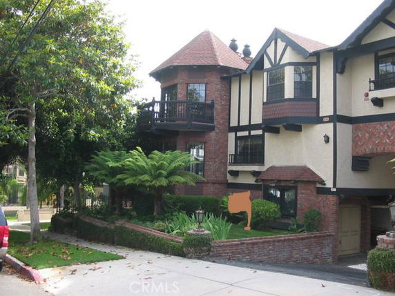 Front view of a multi-story house with Tudor-style architecture and a balcony.
