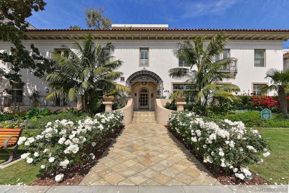 Front view of a two-story building with a central entrance and decorative plants.