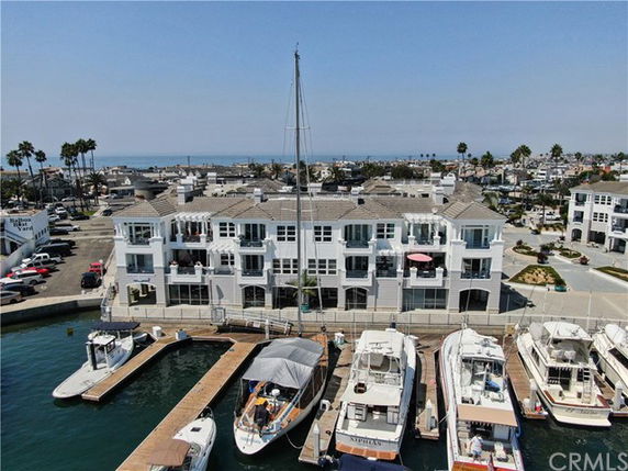 Front view of a multi-story waterfront building with a marina and docked boats.