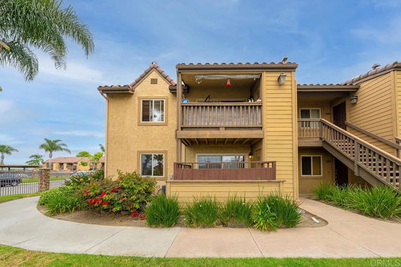 Front view of a multi-story house with balconies and wooden siding.