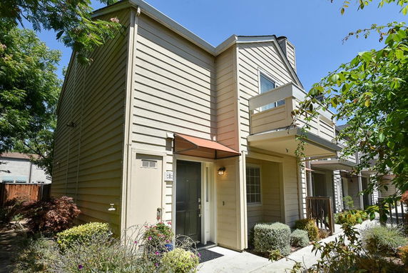 Front view of a two-story house with a small balcony and an entrance covered by a small awning.