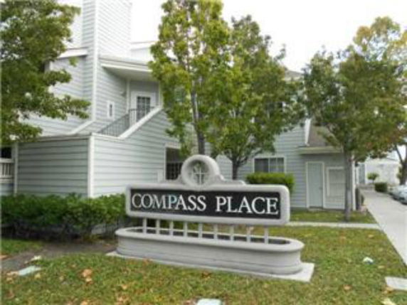 Front view of a multi-story residential building with a sign reading 'COMPASS PLACE' at the forefront.