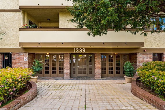 Front view of a building entrance with a brick facade and potted plants.