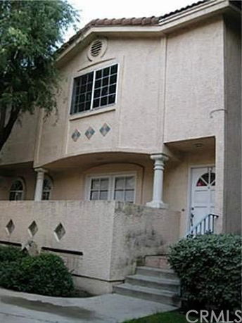 Front view of a two-story house with a stucco exterior and a small porch.
